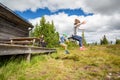 Summer nature side view of children in mid air jumping of a porch landing on grass hill.