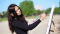 summer, near river, on beach. at sunrise, a beautiful woman artist holds a brush in her hand, draws a picture. she