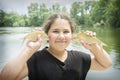 In summer, near the river, a girl holds two breams in her hands Royalty Free Stock Photo