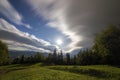 Summer night mountain panorama. Green trees on grassy mountain clearing on cloudy evening sky copy space background, woody hills