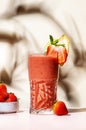 Summer non-alcoholic csmoothie drink with strawberry, banana, syrup, peach juice, lemon and ice in highball glass. Beige pink Royalty Free Stock Photo