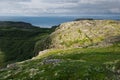 Summer norway landscape - granite high shore, green valley and blue quiet Arctic Ocean in sunny weather.