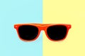 Summer orange sunglasses isolated in pastel blue and yellow split background. Minimal concept image for summer holidays. Royalty Free Stock Photo