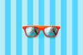 Summer orange sunglasses with palm trees reflections isolated in large blue background with stripes. Royalty Free Stock Photo