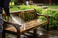 Summer outdoor cleaning person uses pressure washer on wooden garden bench