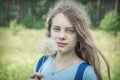 Summer outdoor portrait of a romantic girl with a big fluffy dandelion. the child holds a dry dandelion in his hands Royalty Free Stock Photo