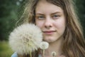 Summer outdoor portrait of a romantic girl with a big fluffy dandelion. the child holds a dry dandelion in his hands Royalty Free Stock Photo