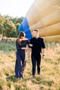 Summer outdoor shot of joyful young couple walking during sunset in green field, posing to camera in front of yellow hot Royalty Free Stock Photo