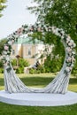 Summer outdoor wedding ceremony decoration. Beautiful white arch of branches and bouquet of white roses, hydrangeas and gypsophila Royalty Free Stock Photo