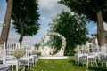 Summer outdoor wedding ceremony decoration. Beautiful white arch of branches and bouquet of white roses, hydrangeas and gypsophila Royalty Free Stock Photo