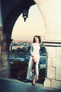 Summer outdoor young pretty elegant girl posing at sunset. Lovely soft back light. View on city buildings and roofs Royalty Free Stock Photo