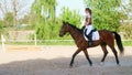 summer, outdoors, girl rider, jockey riding on a thoroughbred beautiful brown stallion, horse, on the training ground Royalty Free Stock Photo