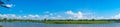 Snow-white clouds on a background of blue sky. Summer panorama of the river with green trees along the shore. Kitoy River Russia Royalty Free Stock Photo