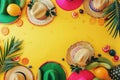 Summer party flat lay with colorful sombreros and tropical fruits on a yellow background