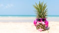 Summer in the party. Hipster Pineapple Fashion in sunglass and listen music on the sand beach beautiful blue sky background.