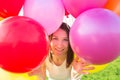 Summer party. Smiling girl looking through colorful air balloons