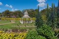 Summer pavilion in public garden with lush spring plants