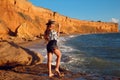 Summer photo of Sexy brunette girl with hat in fashion casual outfit enjpying on the beach at sunset. Freedom summertime vacation Royalty Free Stock Photo