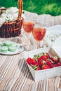 Summer picnic. Box with fresh strawberry, pink lemonade, dessert macaroons, basket with lilac flowers Royalty Free Stock Photo