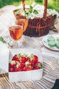 Summer picnic. Box with fresh strawberry, wine, dessert macaroons, basket with lilac flowers Royalty Free Stock Photo