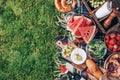 Summer picnic with cake, fruits, cheese, wine and snacks on plaid over green background. Top view. Copy space. Summer Royalty Free Stock Photo
