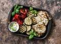 Summer picnic grilled vegetables - eggplant, bell peppers, ciabatta, yogurt sauce, basil in baking sheet on wooden background, top