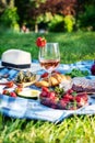 Summer picnic in the park on the grass. Wine, fruit and croissants