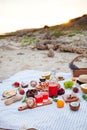 Picnic on the beach at sunset in the white plaid, food and drink