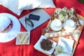 A summer picnic - A tray of food, drinks, glass of minty lemonade in a crystal stem glass on a picnic tray, on a red blanket