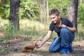 In the summer in the forest the boy feeds the squirrel with nuts