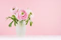 Summer pink decor for home with buttercup flowers - pastel bouquet in exquisite glass vase on white wood table, soft light. Royalty Free Stock Photo