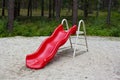 Summer playground. There is a red plastic slide for children on the sand. Royalty Free Stock Photo
