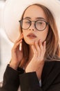 Summer portrait beautiful fashionable young woman in fashion glasses in straw white hat in youth black stylish jacket at sunset. Royalty Free Stock Photo