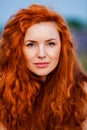 Summer portrait of a beautiful girl with long curly red hair Royalty Free Stock Photo