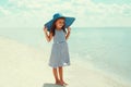 Summer portrait beautiful little girl child wearing a striped dress and straw hat on a beach on sea background Royalty Free Stock Photo