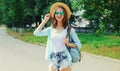 Summer portrait beautiful smiling young woman wearing a straw hat and backpack in the city park Royalty Free Stock Photo