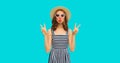 Summer portrait of beautiful young woman blowing her lips sending sweet air kiss wearing straw round hat, striped dress on blue Royalty Free Stock Photo