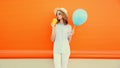 Summer portrait of beautiful young woman drinking fresh juice looking away wearing straw hat on orange background Royalty Free Stock Photo