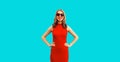 Summer portrait of beautiful young woman posing wearing dress and red heart shaped sunglasses on blue background Royalty Free Stock Photo