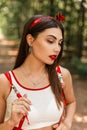 Summer portrait of beautiful young woman with red lipstick and sexy lips in white youth top with fashionable bandana walk on