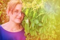 Summer portrait of a brunette girl with glasses, copy space. Smiling woman on a warm day near ivy. Woman face close-up against the Royalty Free Stock Photo