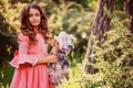 Summer portrait of curly smiling child girl in fairytale princess dress with doll in the forest Royalty Free Stock Photo