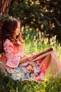 Summer portrait of curly smiling child girl in fairytale princess dress in the forest