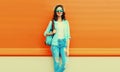 Summer portrait of full-length happy smiling young woman wearing straw hat, backpack and shirt on orange background Royalty Free Stock Photo