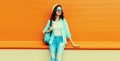 Summer portrait of full length happy smiling young woman wearing straw hat, backpack and shirt on orange background Royalty Free Stock Photo