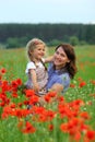 Summer portrait of happy cuddling mother and daughter in the poppies field Royalty Free Stock Photo