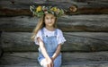 Summer portrait of a happy girl. Cute teenage girl in flower wreath. Background wall of logs