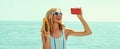 Summer portrait of happy laughing young woman taking selfie with smartphone with papaya on the beach on sea background Royalty Free Stock Photo