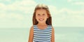 Summer portrait happy smiling little girl child wearing a striped dress on a beach on sea background Royalty Free Stock Photo