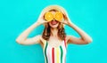 Summer portrait happy smiling woman holding in her hands two slices of orange fruit hiding her eyes in straw hat on colorful blue Royalty Free Stock Photo